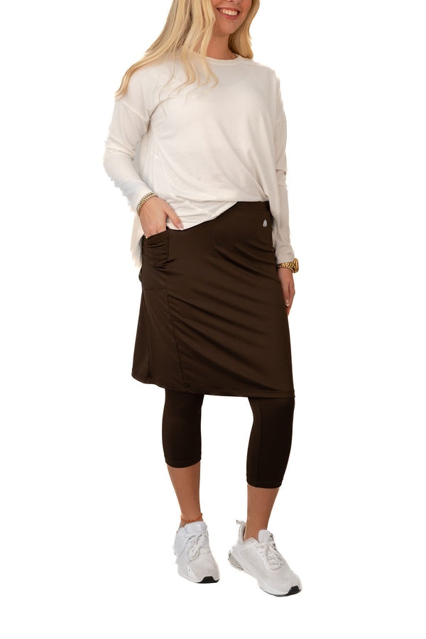 Woman wearing Snoga Athletics brown modest skirt with pockets and black leggings, white sneakers