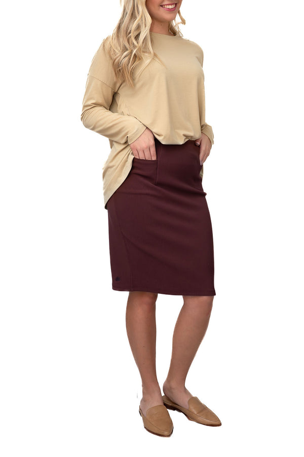 Woman modeling Snoga Athletics modest activewear: beige long sleeve top, maroon knee-length skirt
