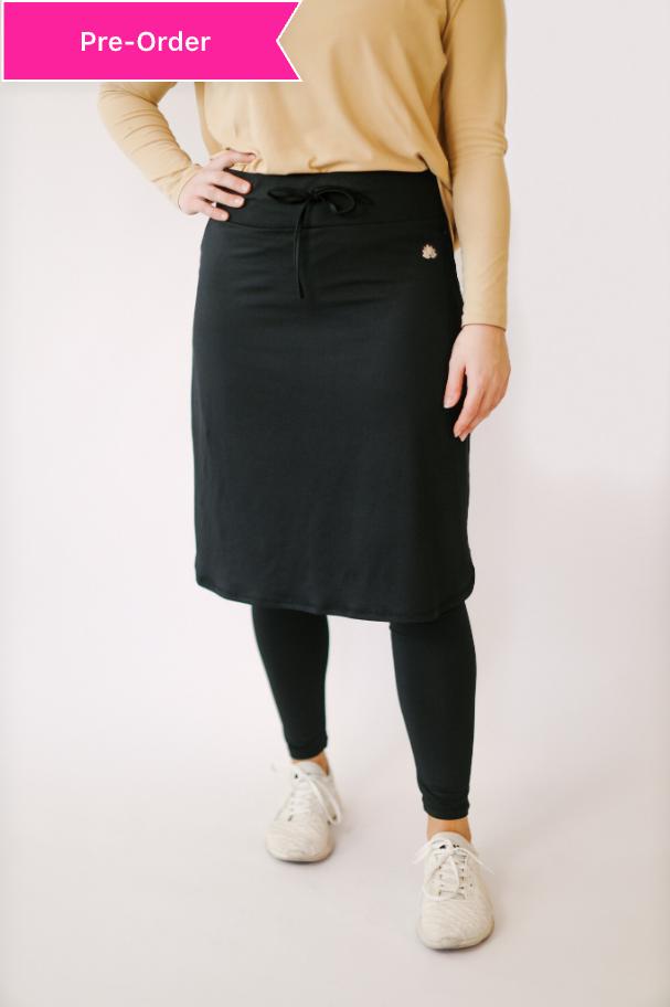 Woman wearing Snoga Athletics black ankle drawstring skirt with leggings and white sneakers
