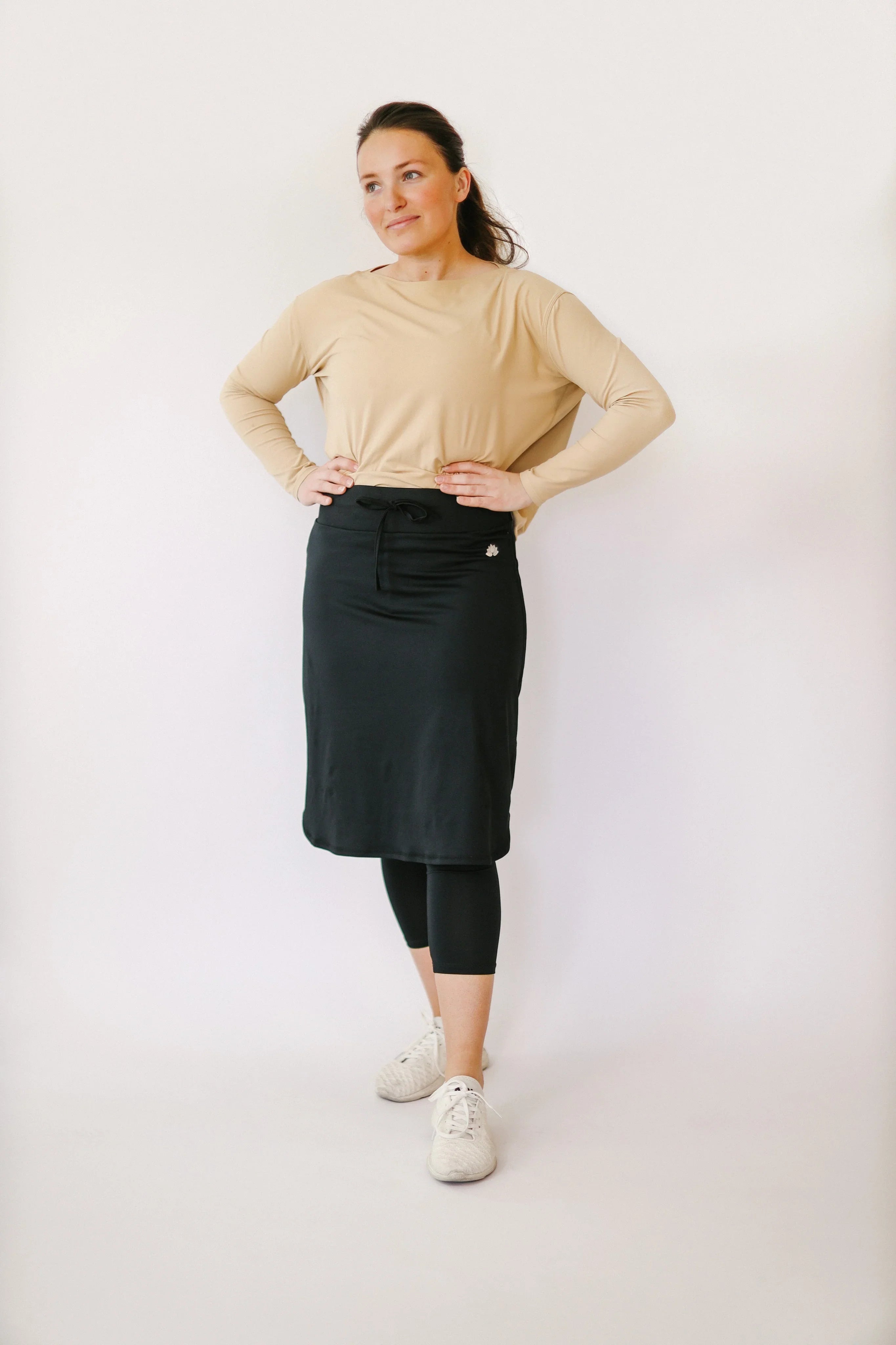 Woman wearing Snoga Athletics black drawstring capri skirt with leggings and beige top