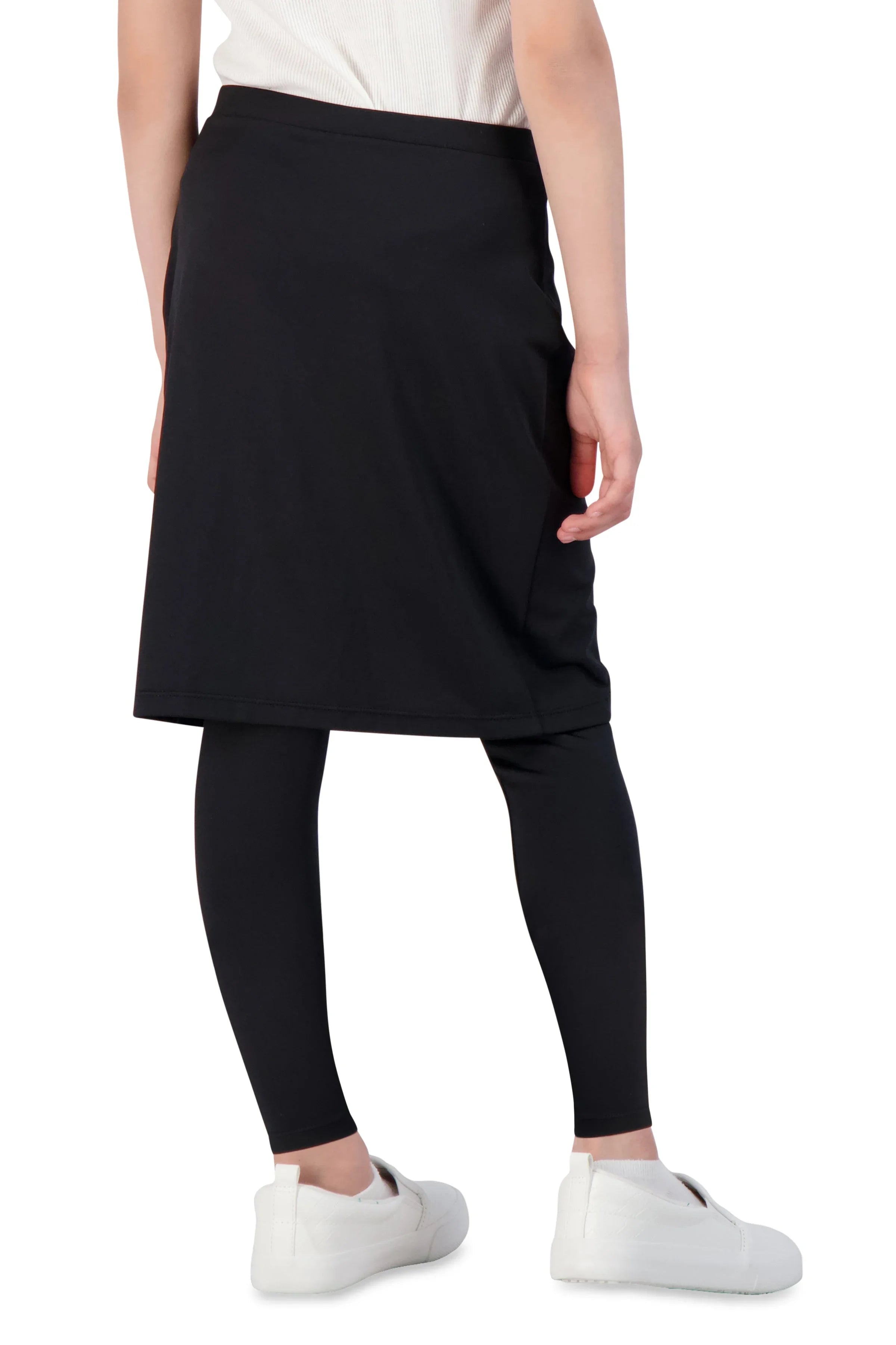 Girl in black faux wrap ankle skirt leggings by Snoga Athletics, white shoes, back view