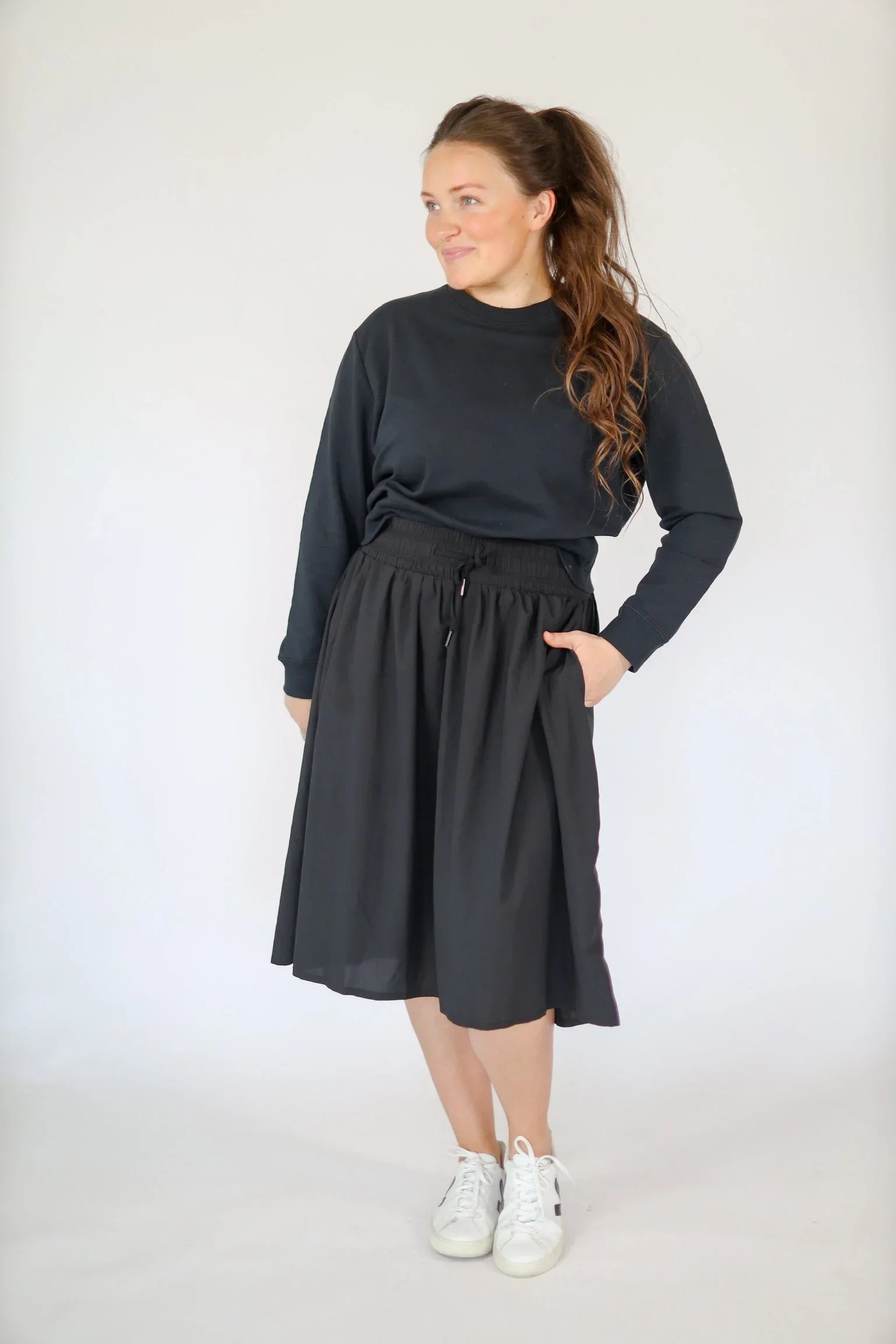 Woman wearing Snoga Athletics black high-rise drawstring modest skirt and sweatshirt