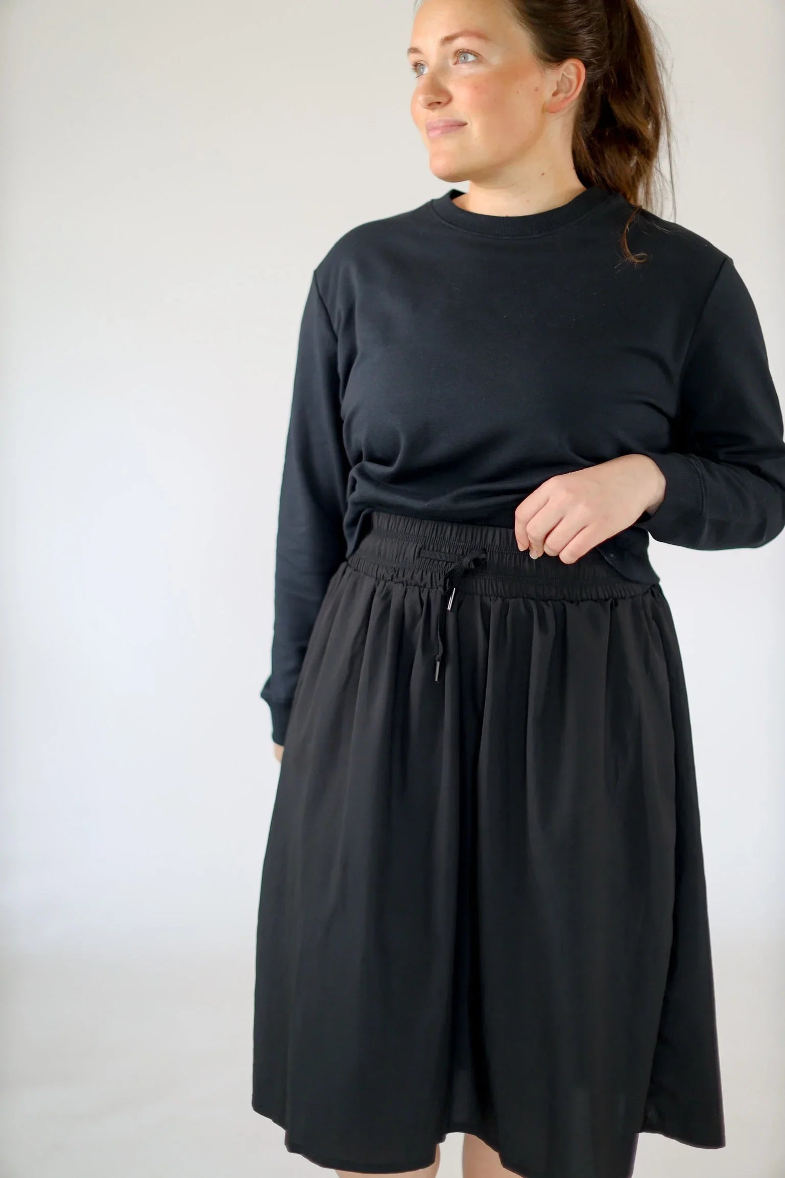 Woman wearing Snoga Athletics black high rise drawstring modest athletic skirt