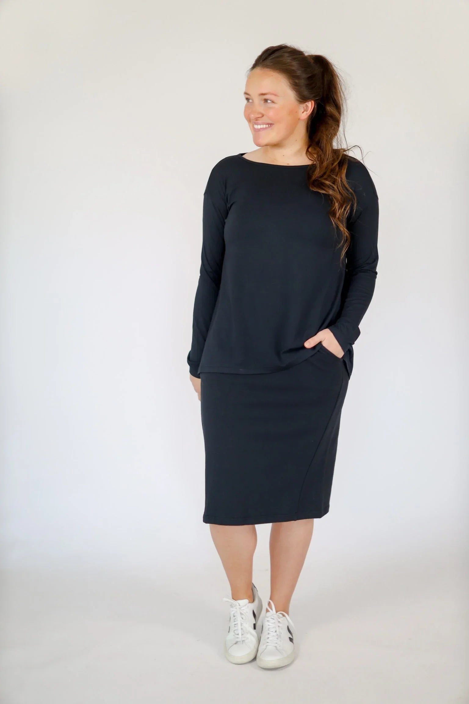 Woman wearing Snoga Athletics black butter soft boat neck tee with matching midi skirt