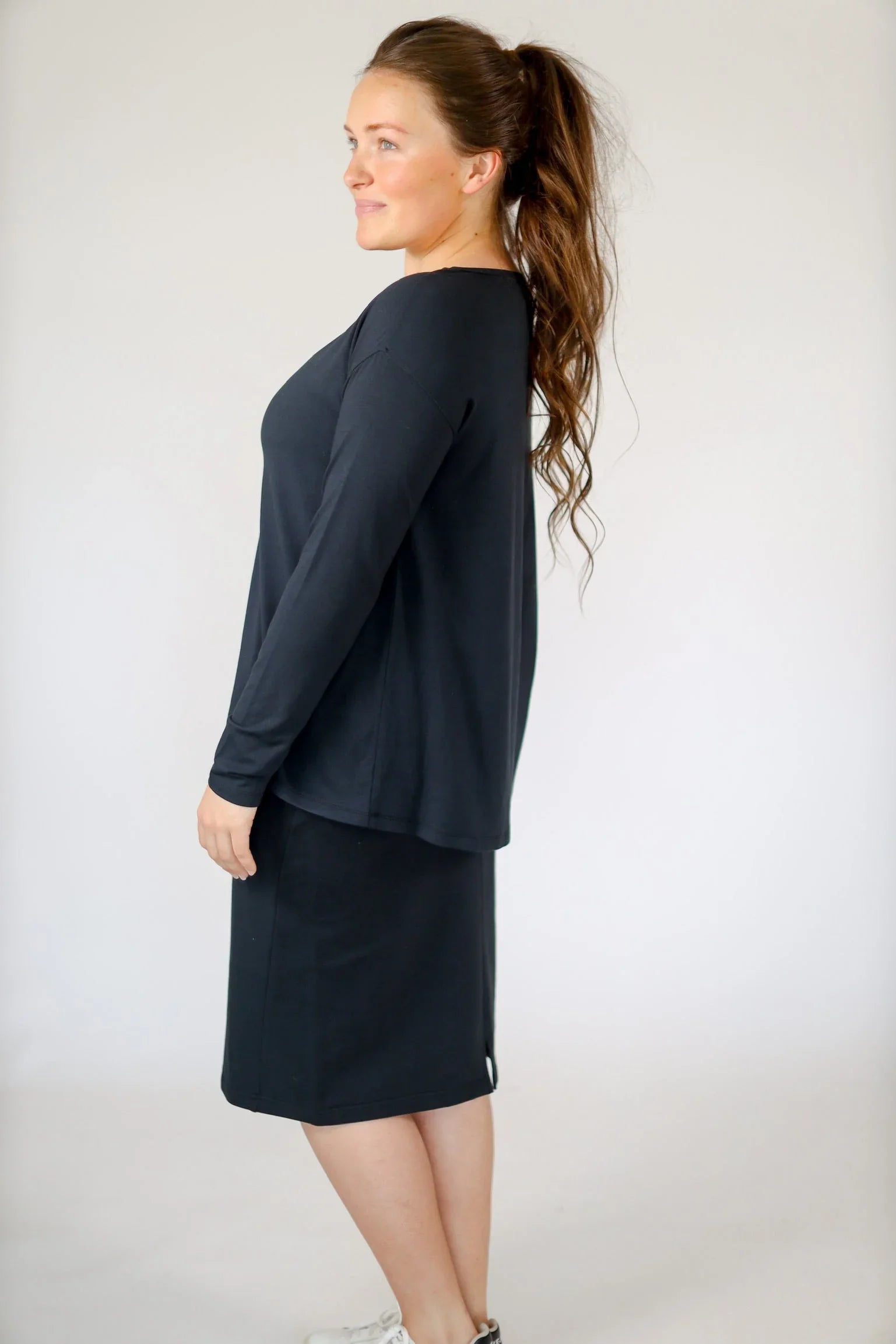 Woman wearing Snoga Athletics black butter soft boat neck tee and matching skirt