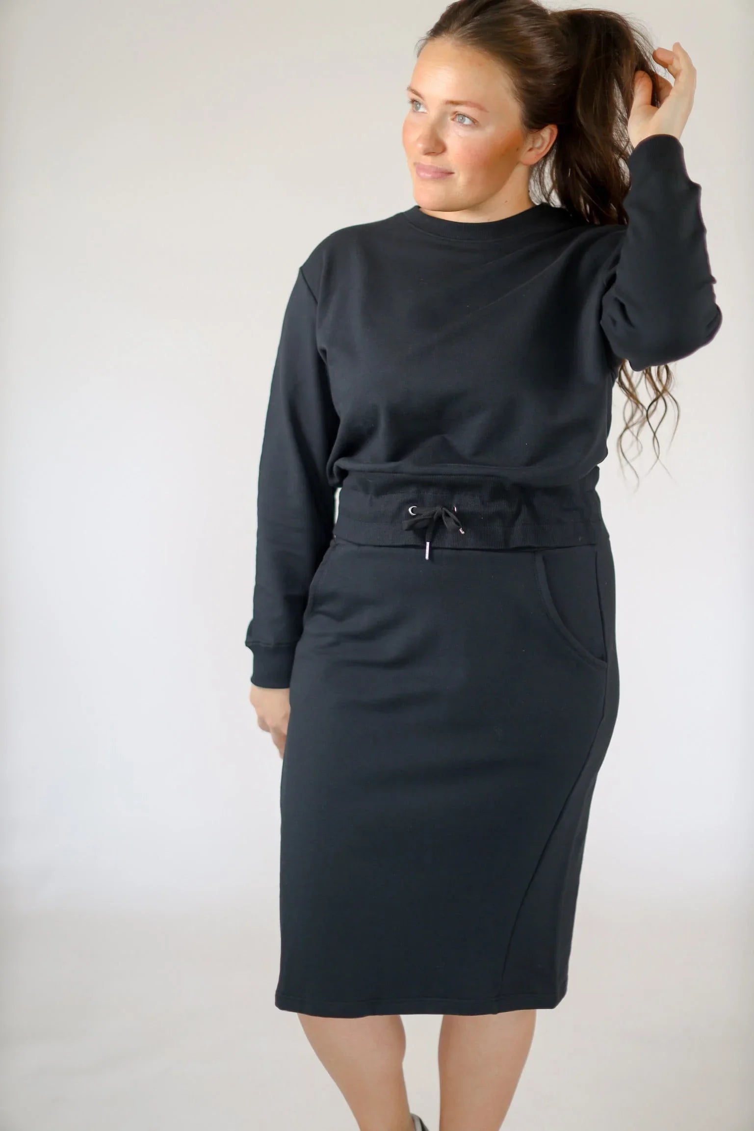 Woman wearing a black cropped drawstring pullover sweatshirt by Snoga Athletics