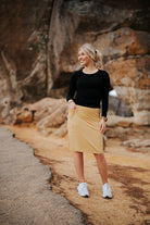 Woman in Snoga Athletics modest activewear skirt and black top standing outdoors on rocky path