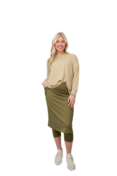 Woman in modest activewear with olive skirt, leggings, and beige top by Snoga Athletics