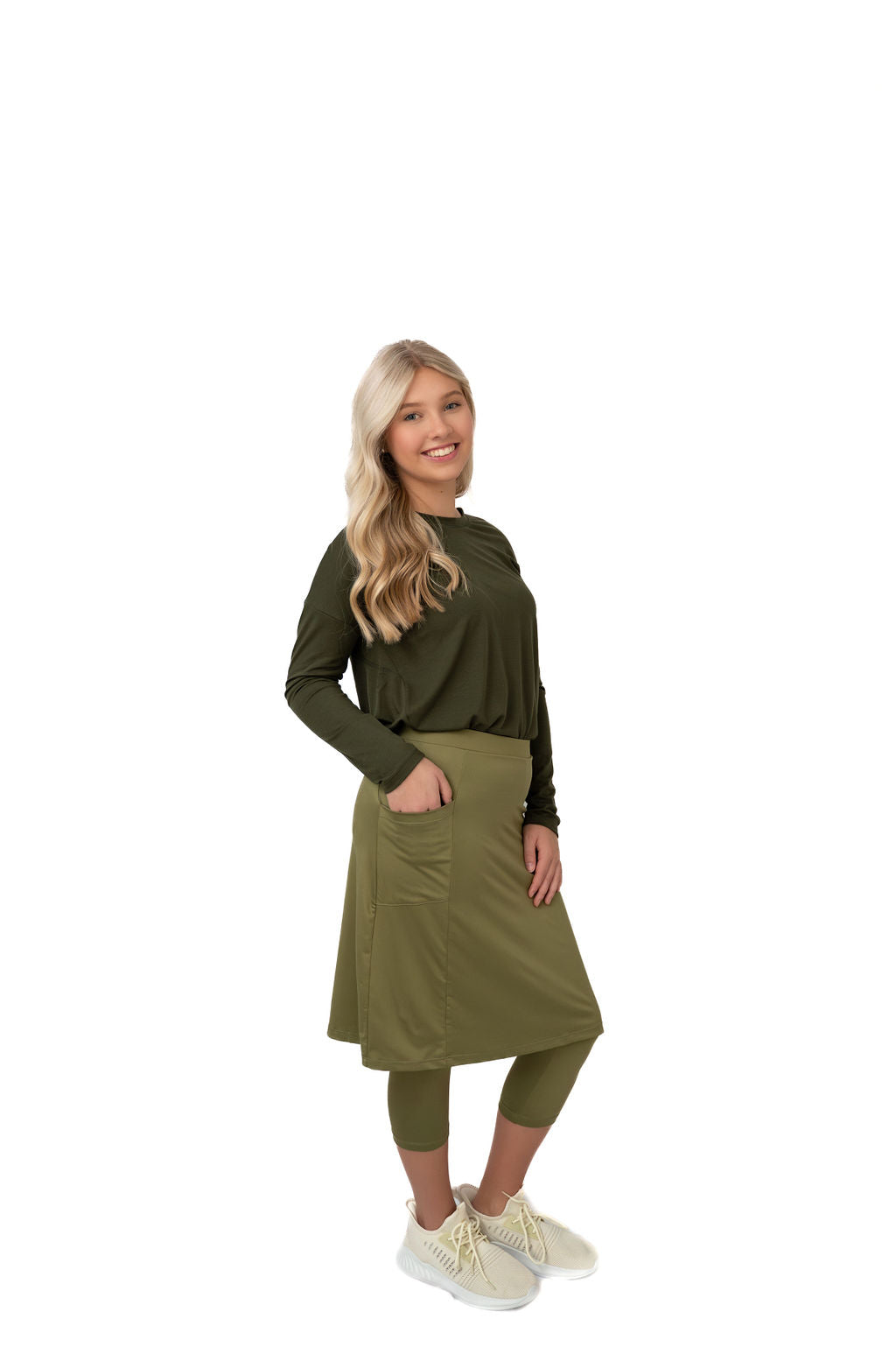 Woman modeling olive green modest activewear set with skirt, leggings, and long-sleeve top from Snoga Athletics