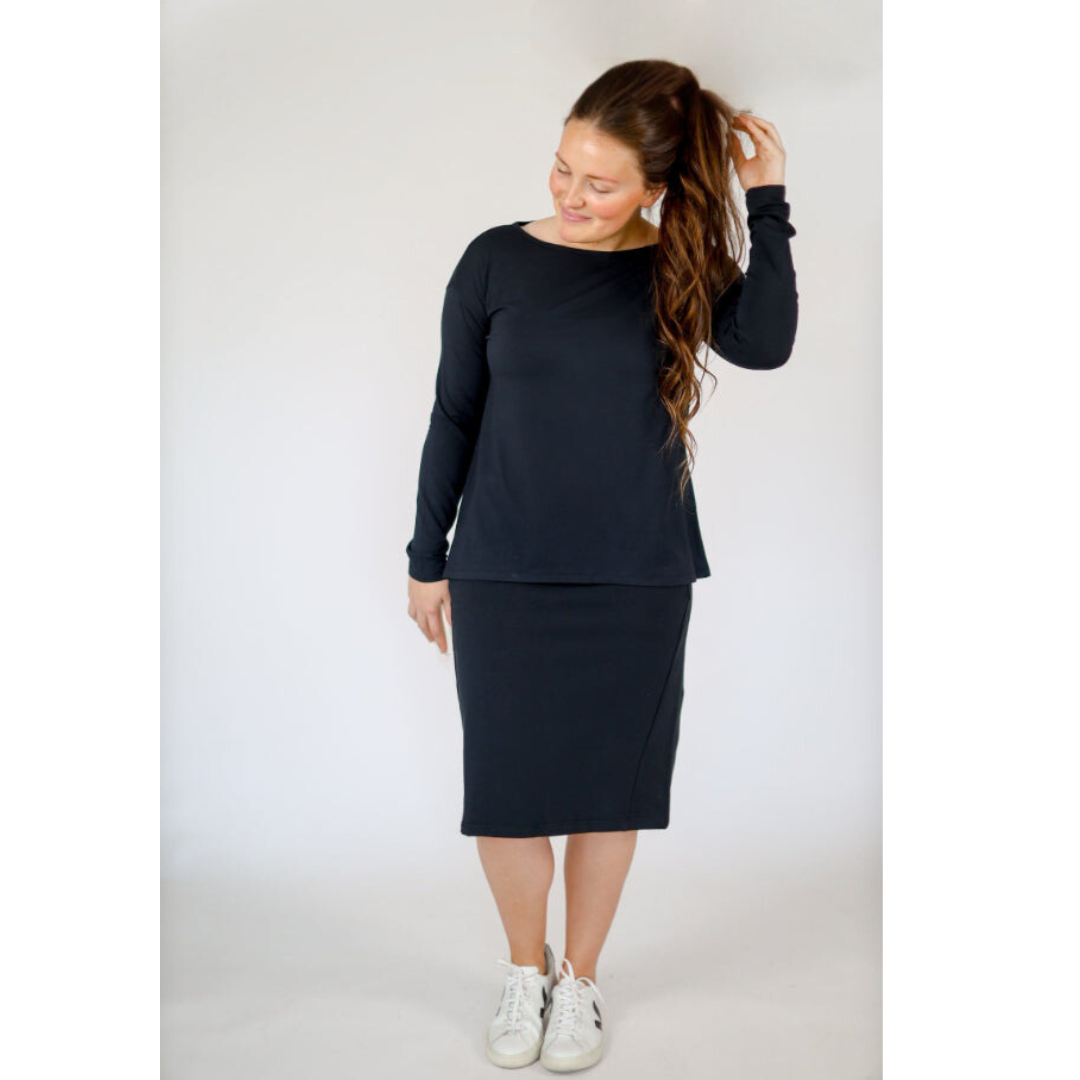 Woman in black modest activewear skirt set by Snoga Athletics, white sneakers, studio background