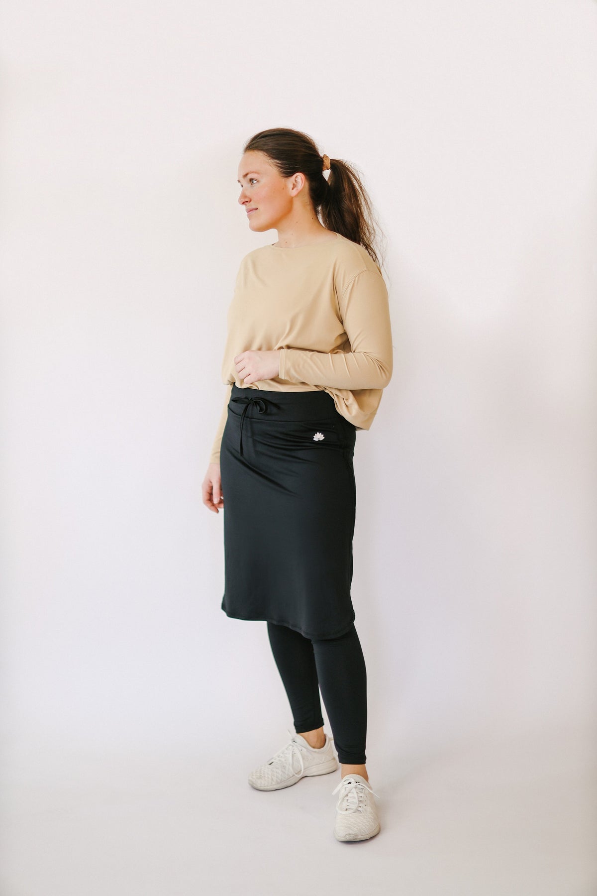 Woman in Snoga Athletics black ankle drawstring skirt with leggings and tan top