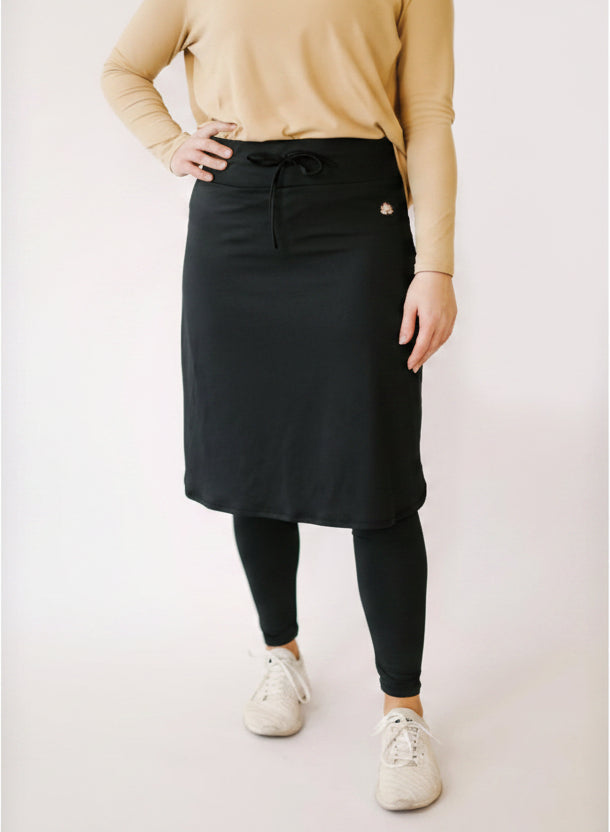 Woman wearing Snoga Athletics black ankle drawstring skirt with leggings and white sneakers