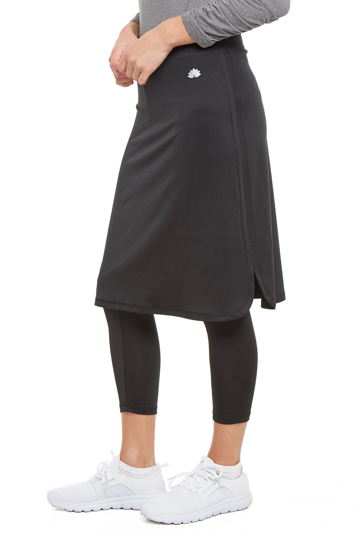 Woman wearing Snoga Athletics black cropped skirted leggings with side slit and white sneakers