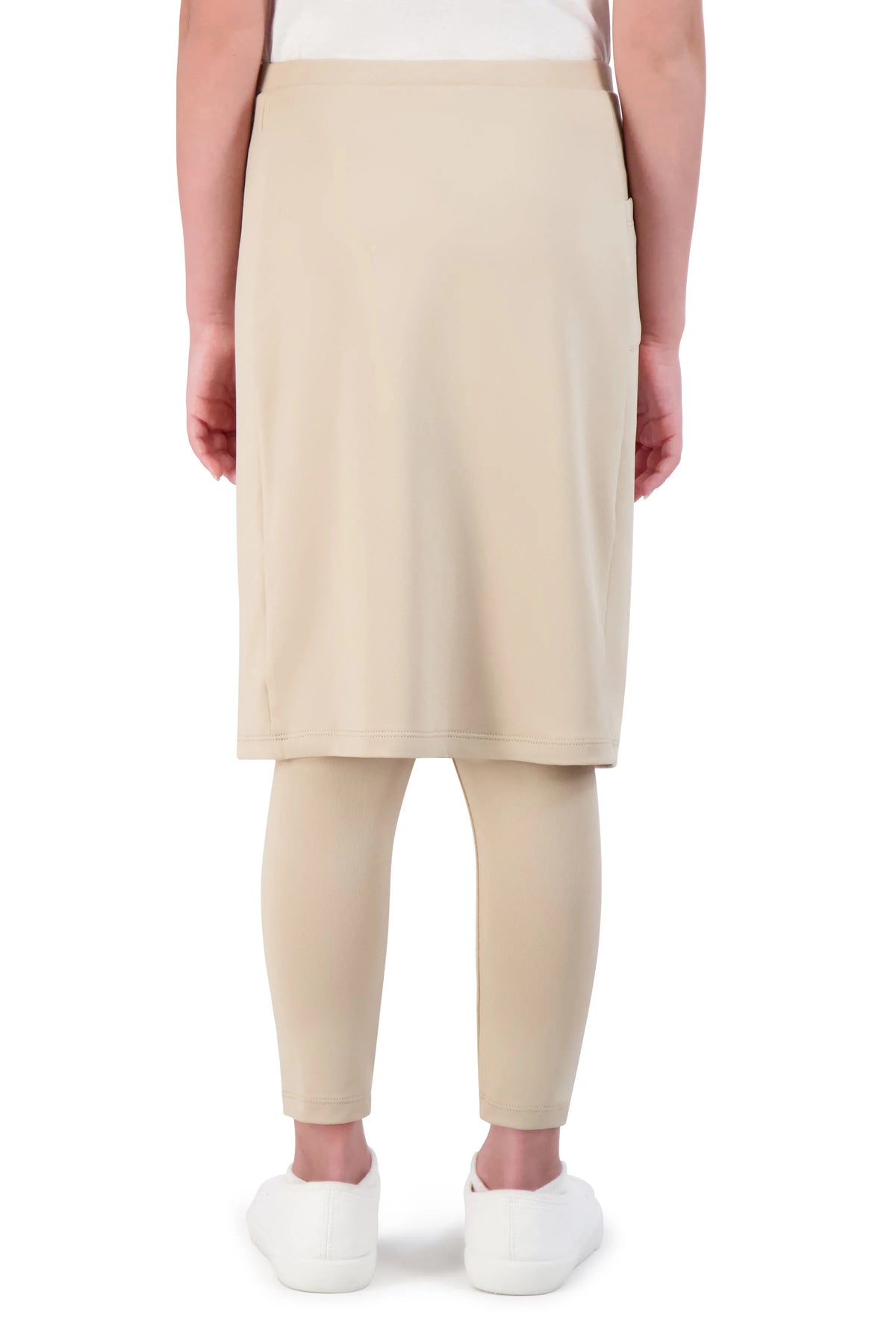 Girl wears Snoga Athletics beige ankle-fit skirt leggings, back view, white sneakers