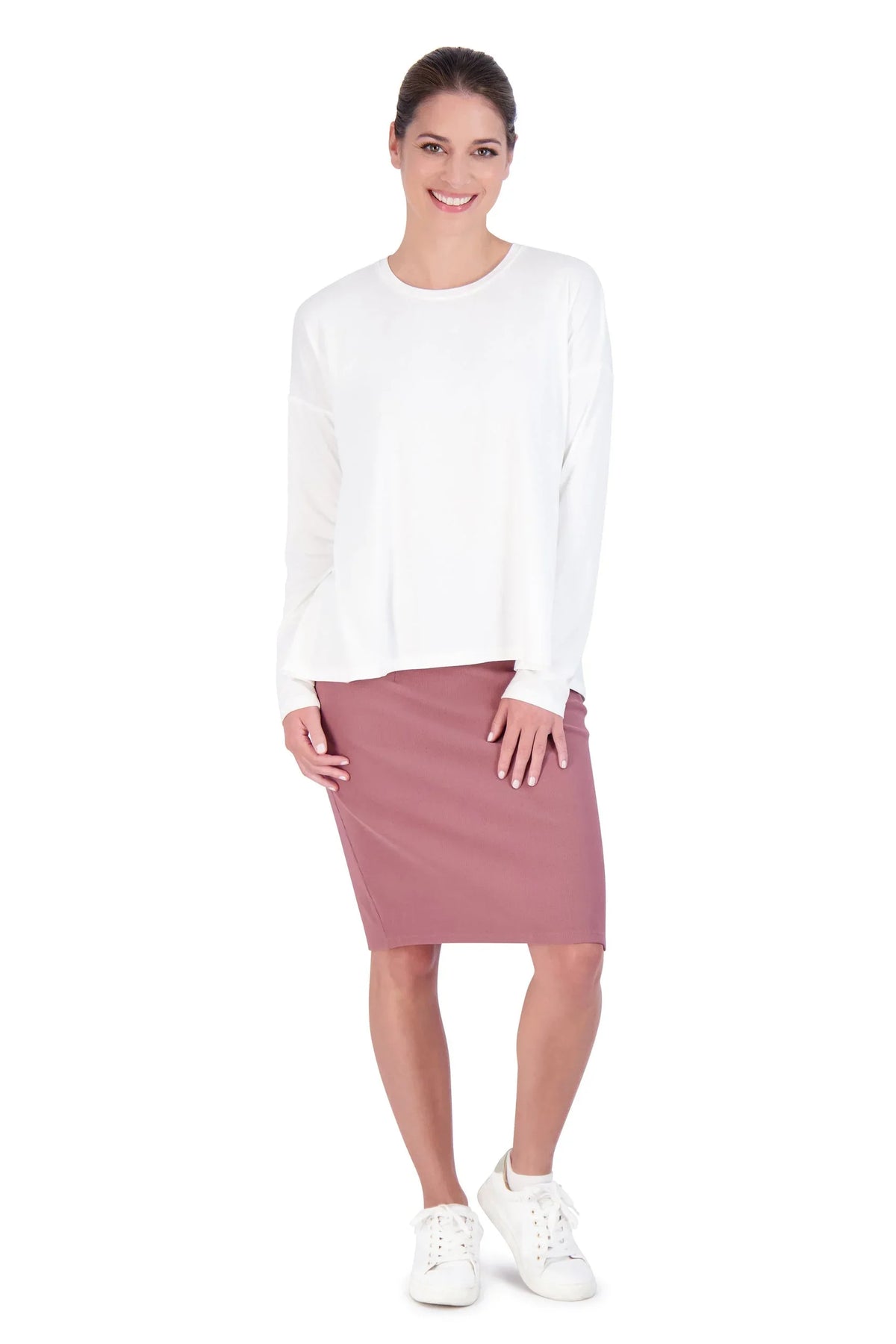 Woman modeling Snoga Athletics white long sleeve shirt with mauve skirt and white sneakers