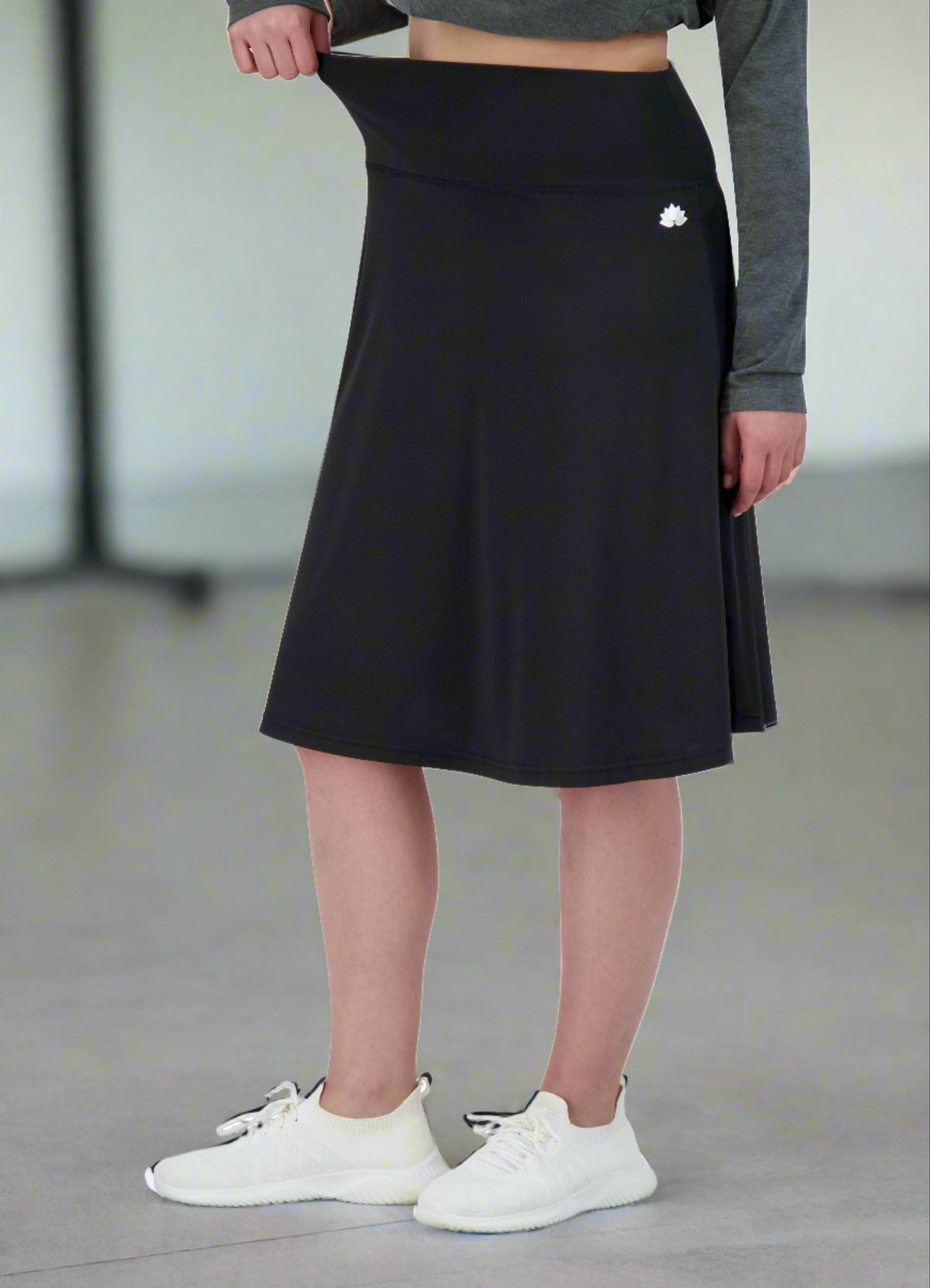 Woman wearing Snoga Athletics black modest athletic skirt with wide waistband and logo