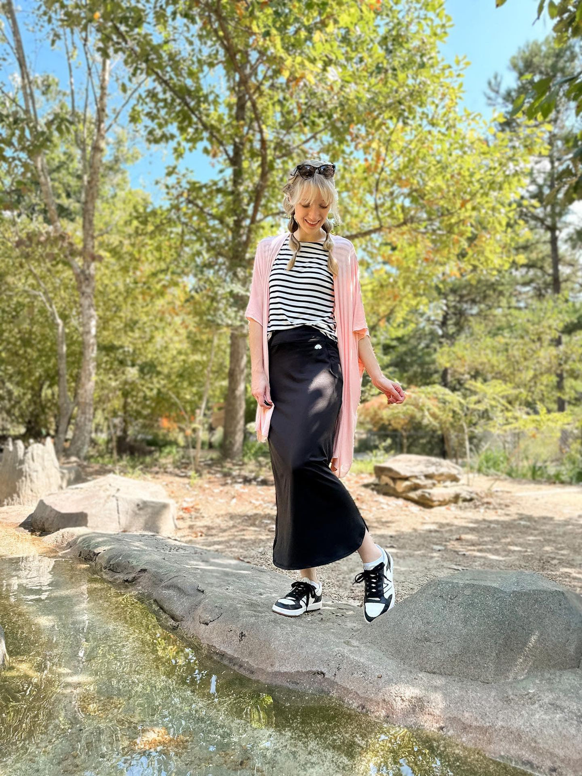 Woman outdoors wearing Snoga Athletics black maxi active skirt, striped shirt, pink cardigan