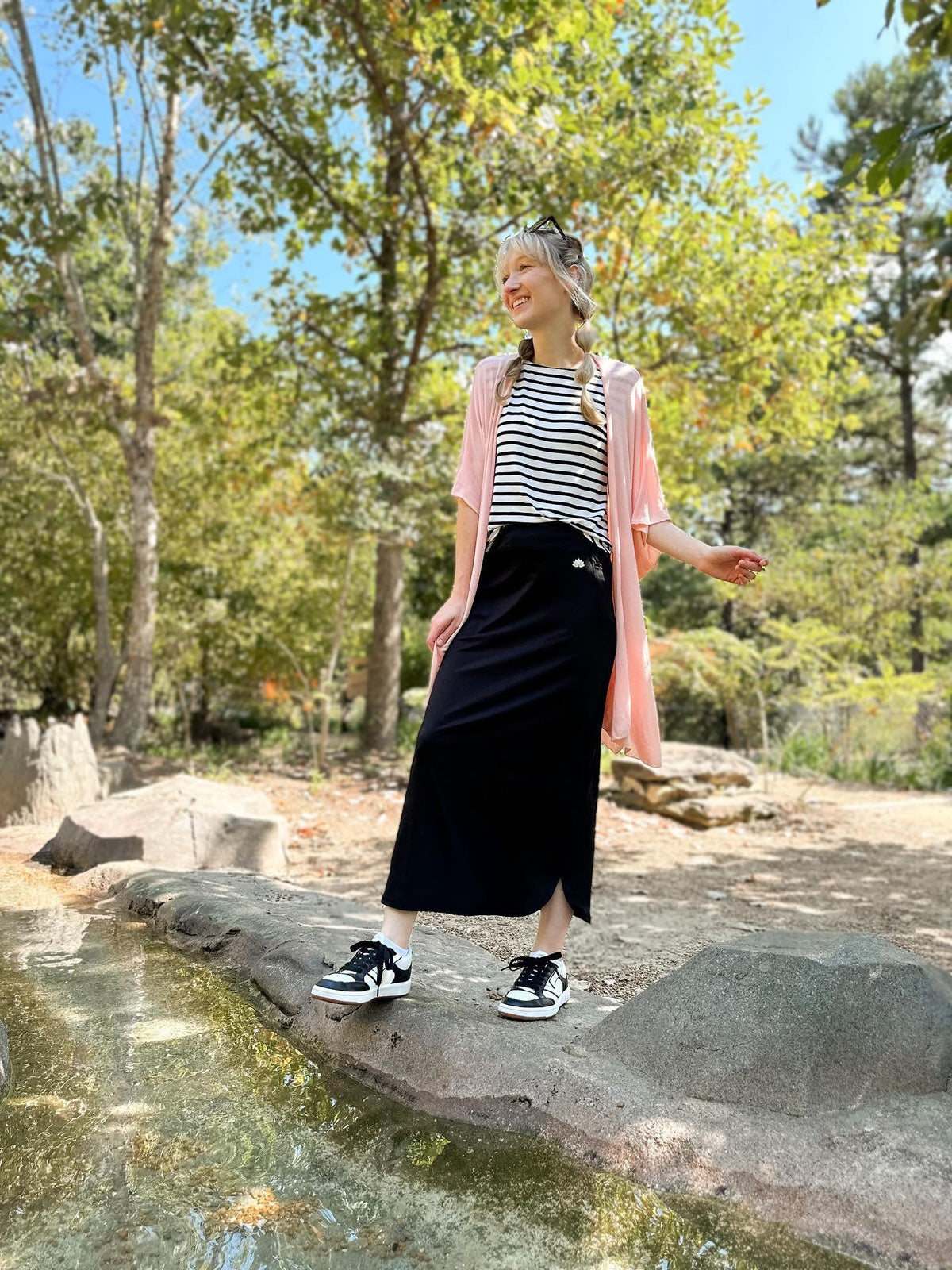 Woman outdoors wearing Snoga Athletics black maxi active skirt with pockets, striped top, and sneakers
