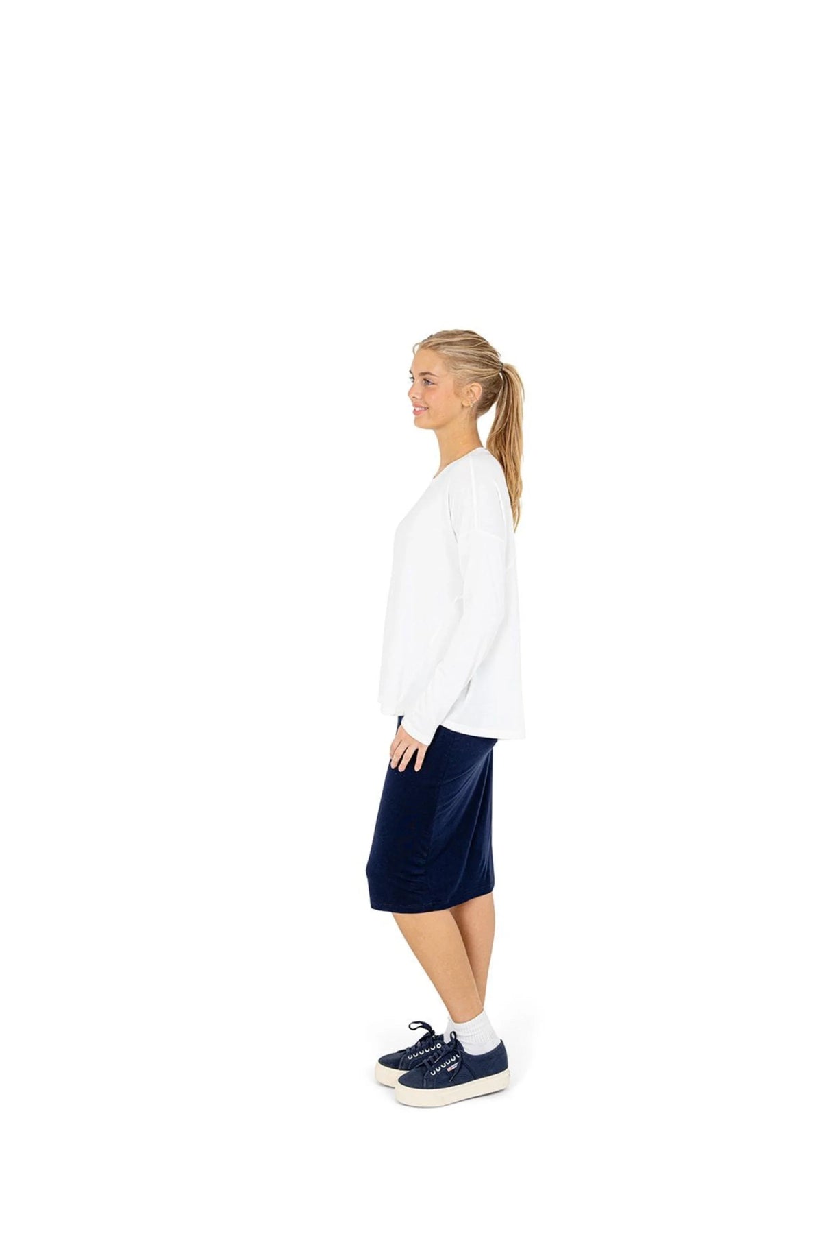 Woman in navy athletic skirt and white top by Snoga Athletics, side view on white background