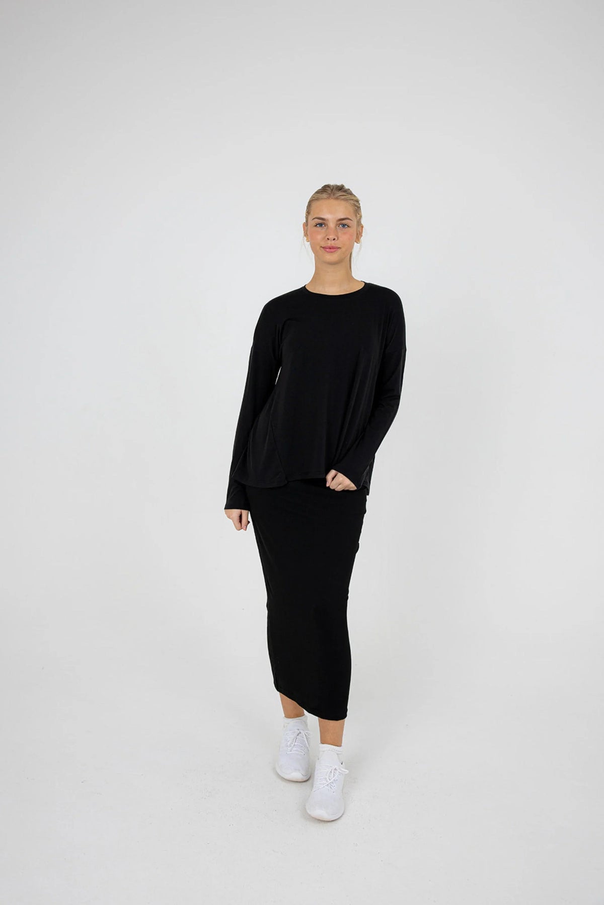 Woman wearing Snoga Athletics black modest t-shirt and skirt set, white sneakers