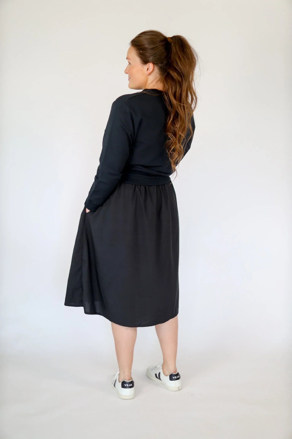 Woman modeling black high-rise athletic skirt by Snoga Athletics, back view, casual style