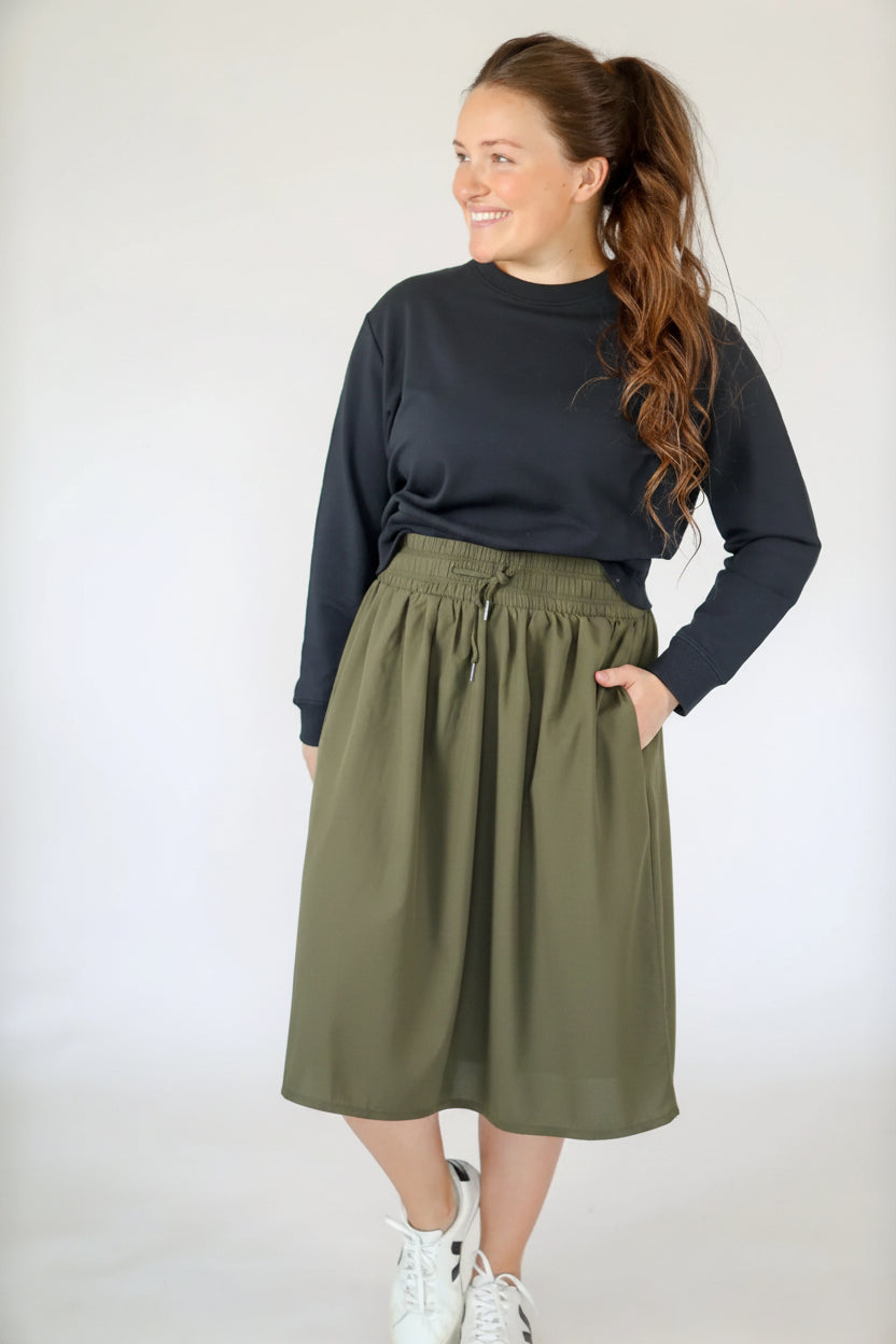 Woman wearing Snoga Athletics black high-rise drawstring modest skirt and sweatshirt