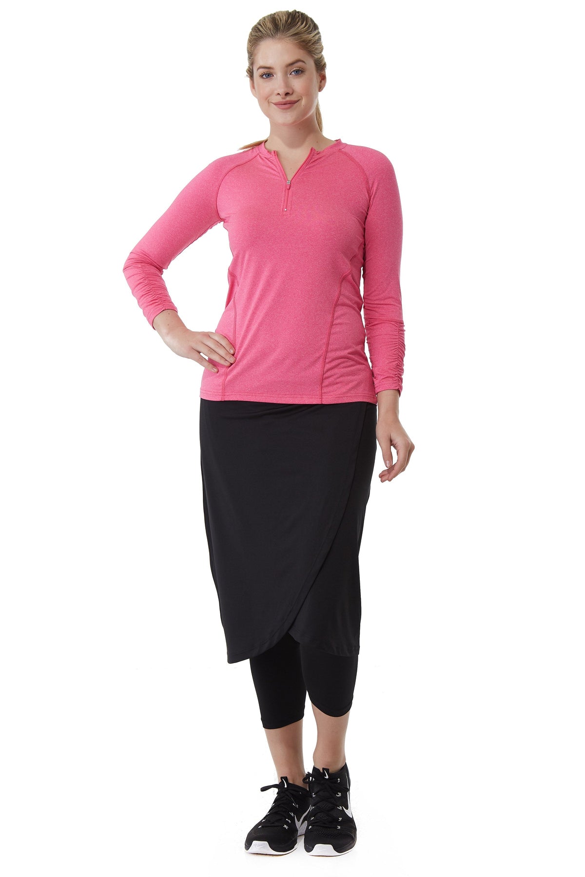 Woman in Snoga Athletics modest activewear, pink long-sleeve top, black faux wrap skirt with leggings