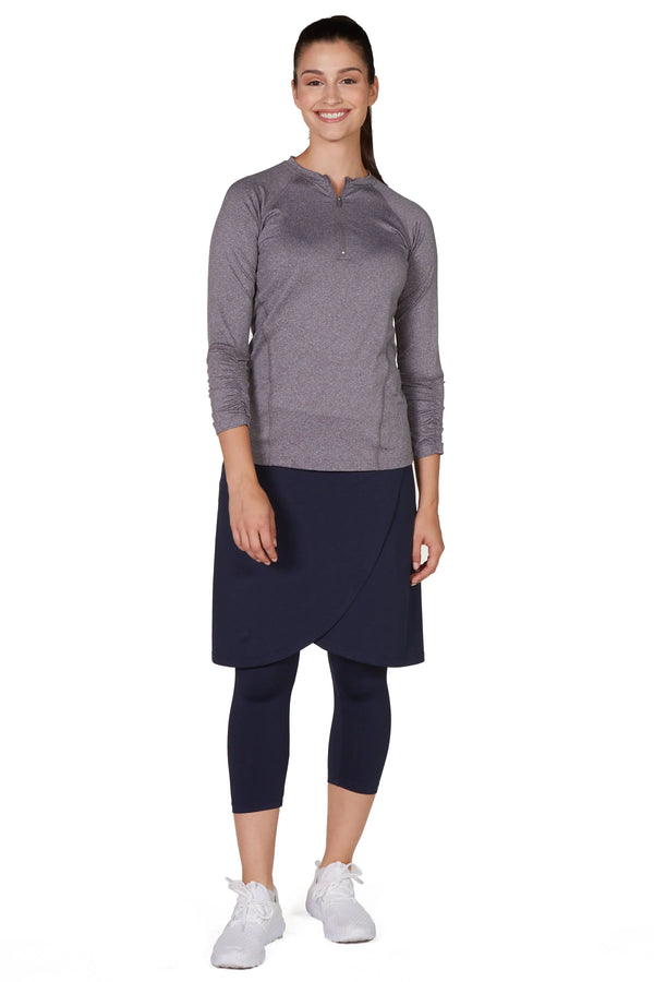 Woman modeling Snoga Athletics navy faux-wrap skirt with attached leggings and gray long sleeve top