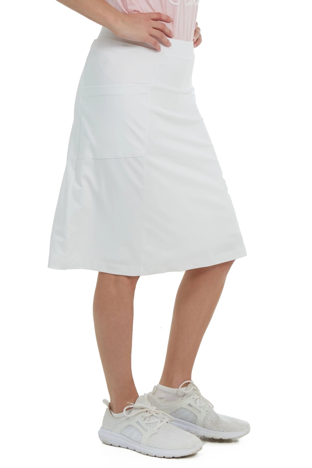 Woman wearing white athletic skort by Snoga Athletics, side view, with sneakers
