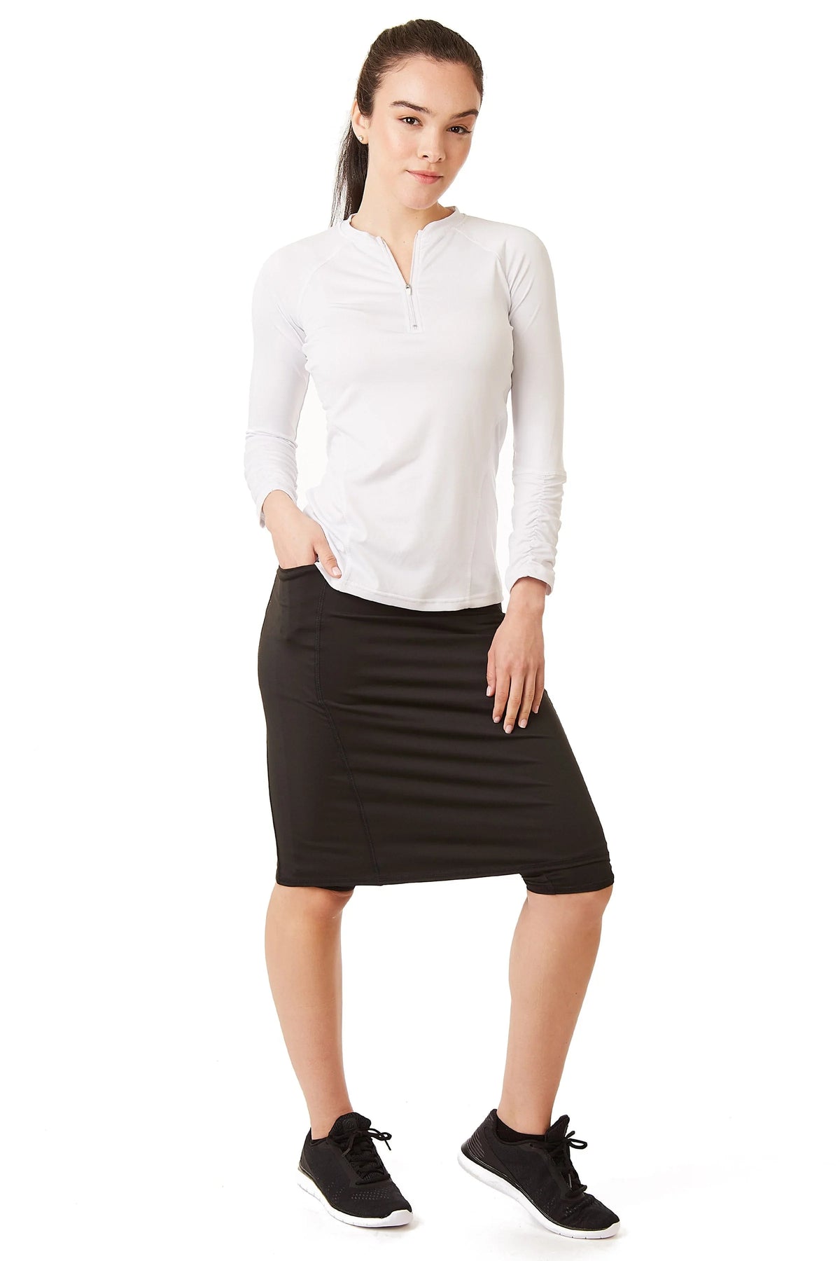 Woman wearing Snoga Athletics black modest athletic skirt with attached shorts and white long sleeve top