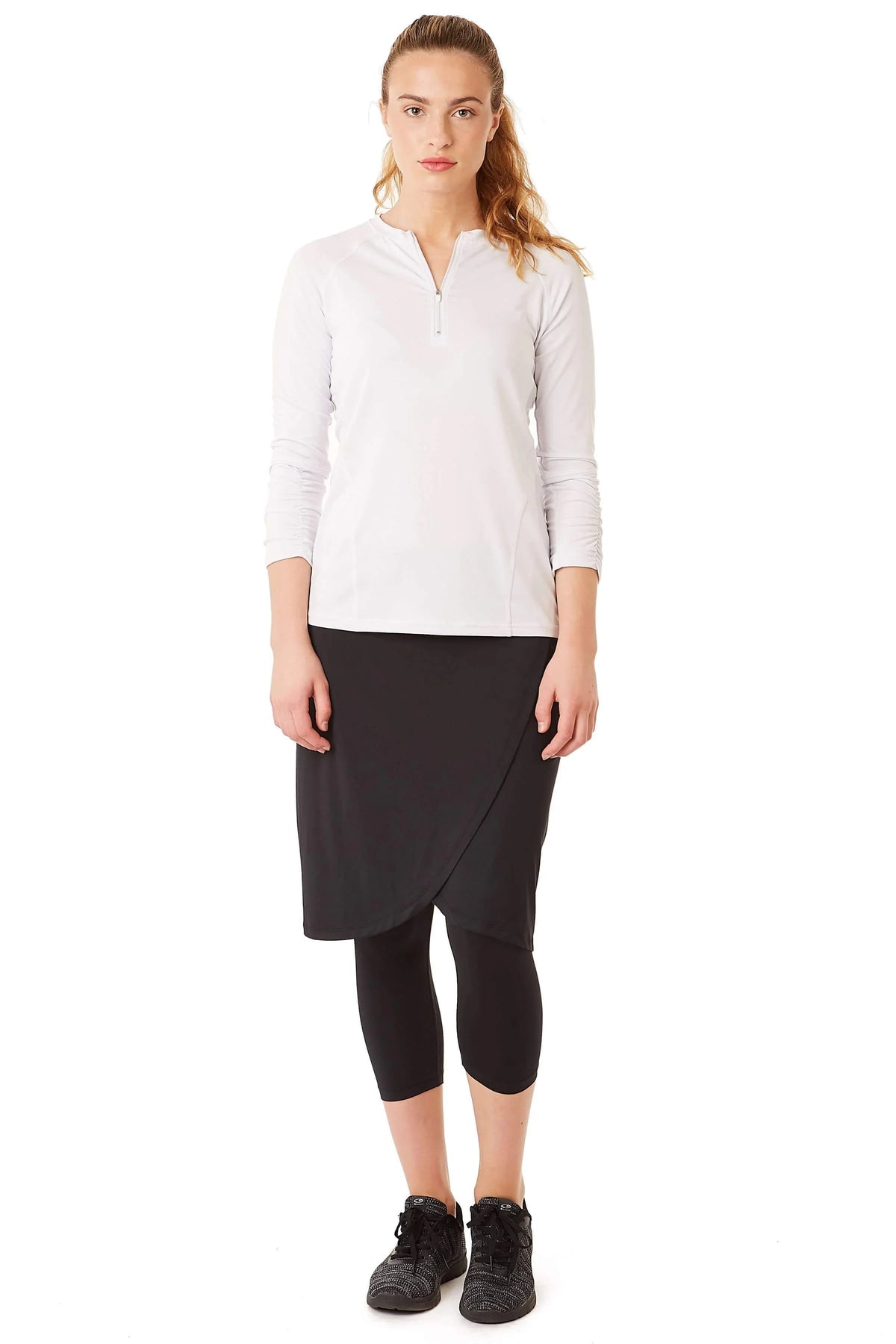 Woman wearing Snoga Athletics black faux wrap skirted leggings and white zip top