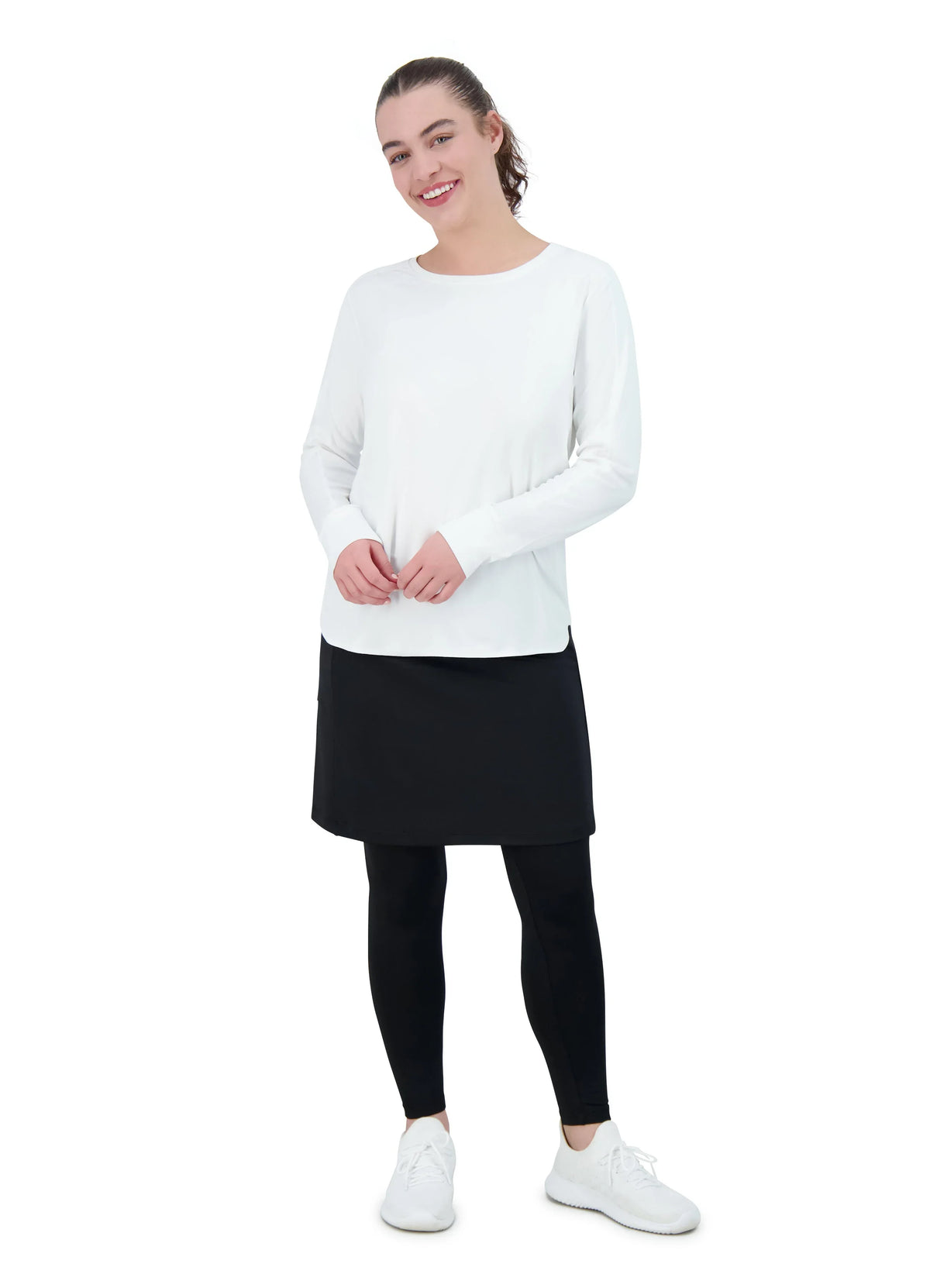 Woman in Snoga Athletics white relaxed fit all day active top, black skirt, and leggings